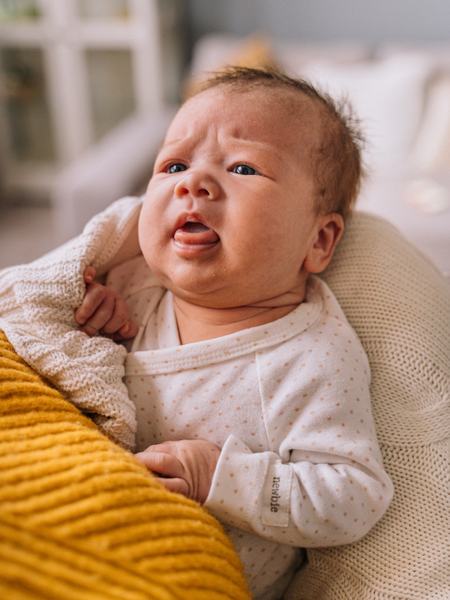 Teilaufnahme eines Babys, welches die Stirn runzelt und den Mund offen hält, dabei ist die Zunge deutlich zu sehen.