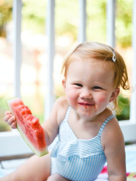 Aufnahme es sitzendes Kindes, das ein Stück Melone in der Hand hält.