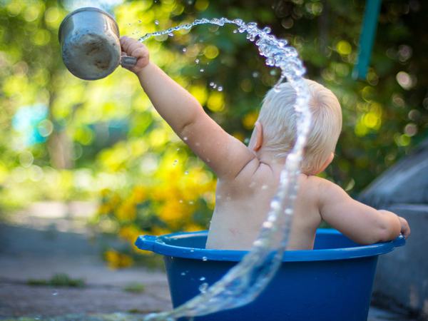 Aufnahme eines Kleinkindes, welches mit Wasser spielt.