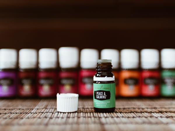 Eine Reihe von Fläschchen mit ätherischen Ölen von Young Living. Eines, Peace and Calming, ist offen und der Deckel liegt daneben.