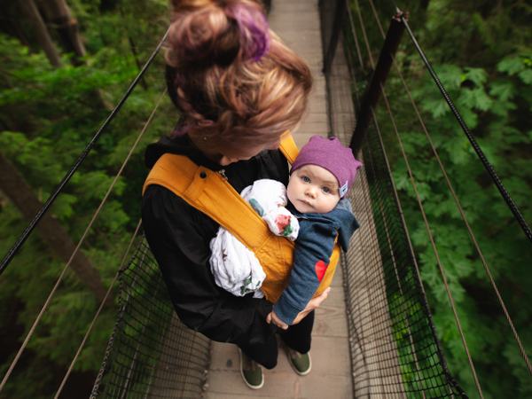 Aufnahme einer Frau von schräg oben, welche ein Baby in einer Tragehilfe trägt.