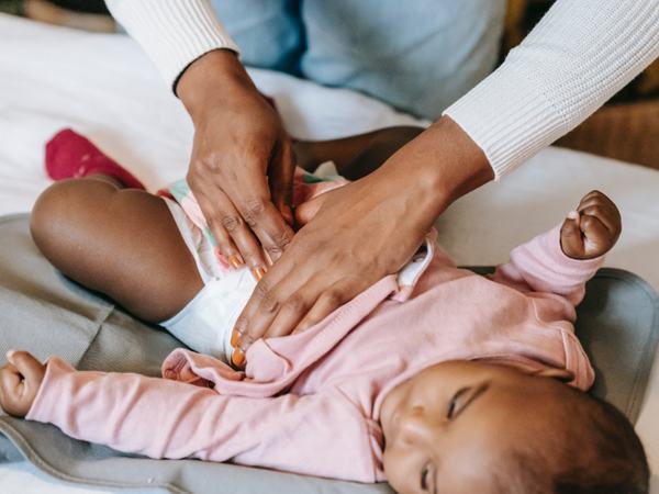 Detailaufnahme einer Hand, die den Bauch eines Babys massiert.