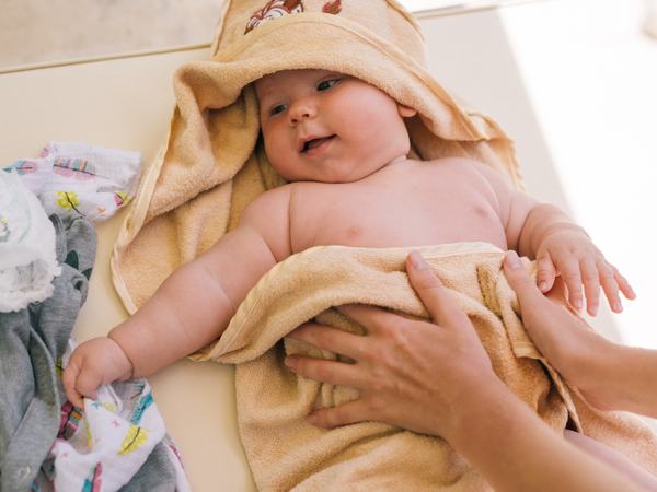 Aufnahme eines liegenden Babys, welches in ein Handtuch gewickelt ist.