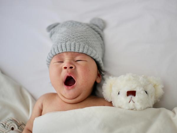Ein Baby mit Mütze. Es gähnt.