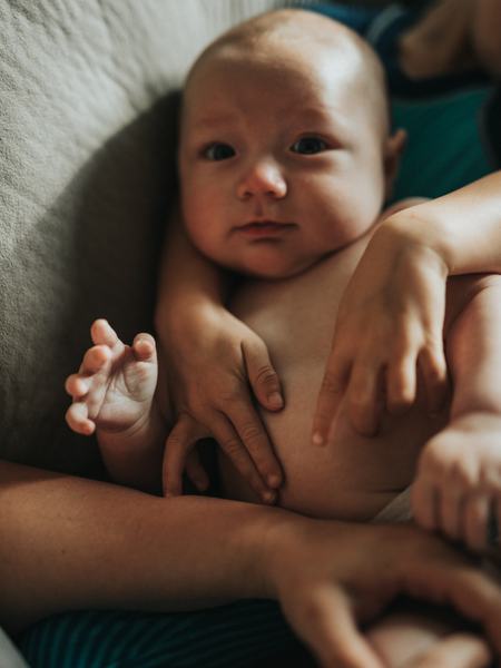 Aufnahme eines Babys, welche mit Händen gestreichelt wird.