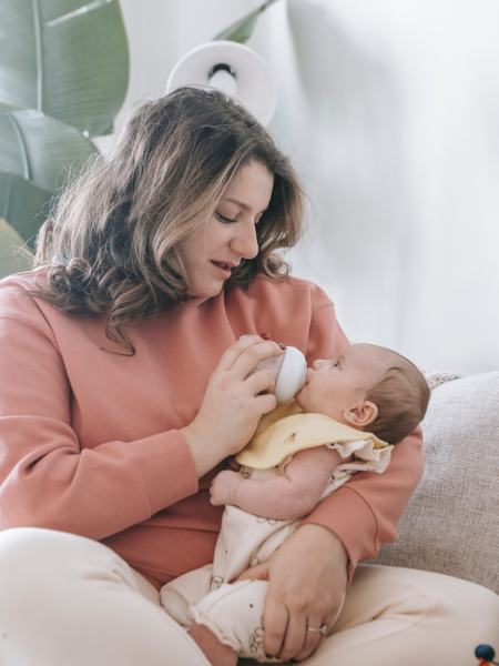 Eine weitere Aufnahme, wie ein Baby mit der Flasche gefüttert wird - in einer aufrechten Position.