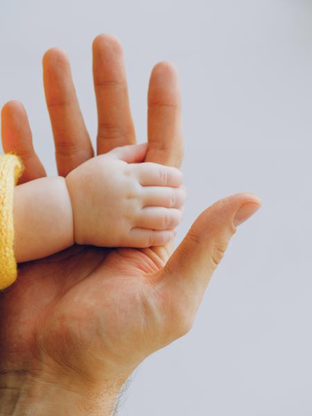 Eine Babyhand liegt in der Hand eines Erwachsenen.