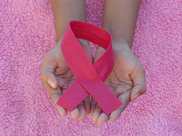 Eine in Händen gehaltene pinke Schleife, als Symbol für Brustkrebs.