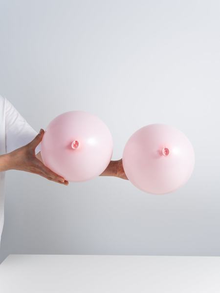 Aufnahme von zwei rosa Luftballons, welche in Händen gehalten werden.