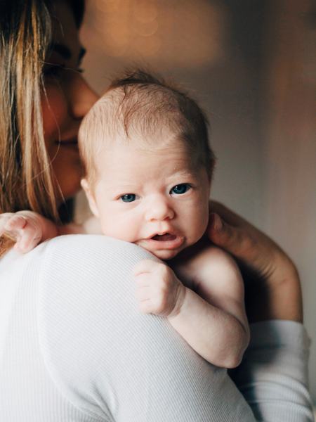 Aufnahme eines Babys, welche über die Schulter gehalten wird.