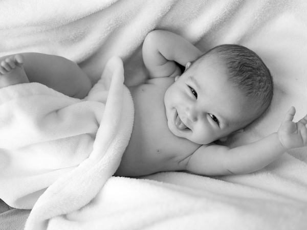Aufnahme eines auf einer Decke liegenden lachenden Babys.