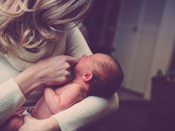 Aufnahme eines Babys, welches auf dem Arm getragen wird und scheinbar Hunger hat.