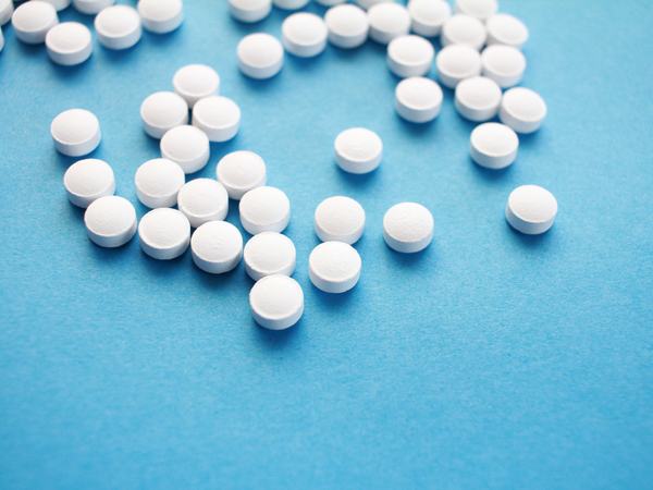 Aufnahme von weißen, runden Tabletten vor einem blauen Hintergrund.