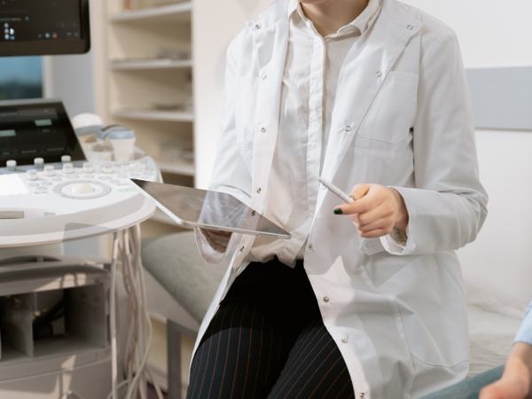 Shot of a woman in a white coat holding a tablet.