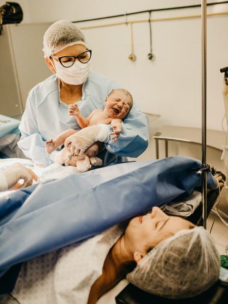 Aufnahme einer Kaiserschnittgeburt, bei der das Baby gerade der Mutter gezeigt wird.