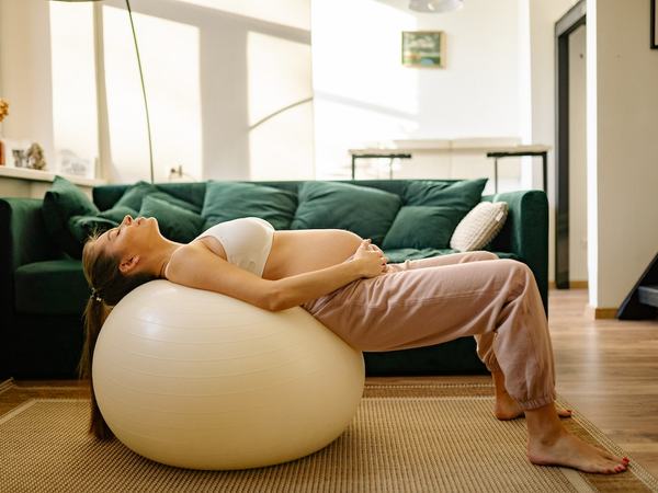 Aufnahme einer Schwangeren, welche mit dem Rücken auf einem Gymnastikball liegt.