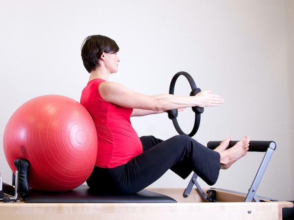Aufnahme einer Schwangeren, welche Sportübungen mit Geräten macht.