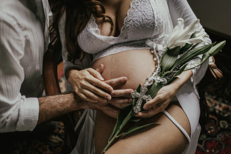 Eine Schwangere Frau wird von ihrem Partner im Arm gehalten, während sie Geburtswehen hat.