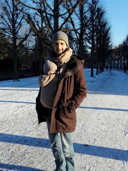 Julias Mann trägt den gemeinsamen Sohn in einer Schneelandschaft vor dem Bauch.