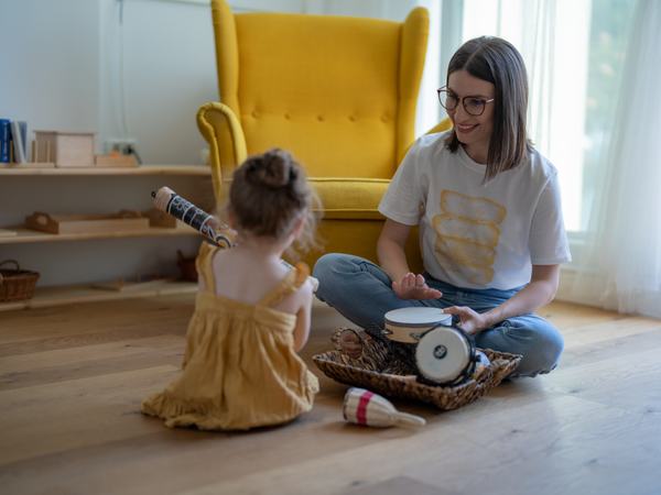 Aufnahme einer Frau, welche mit einem Kind mit Instrumenten spielt.