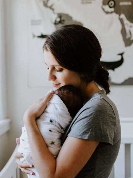 Aufnahme einer Frau, welche ein in ein Tuch gewickeltes Baby hält.