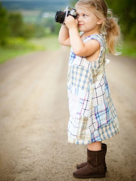 Ein Kind hält eine Kamera in der Hand und schaut durch sie hindurch.