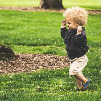 Ein Kleinkind läuft über eine Wiese.
