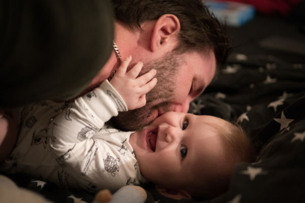 Ein Vater beugt sich über sein Baby und küsst es.