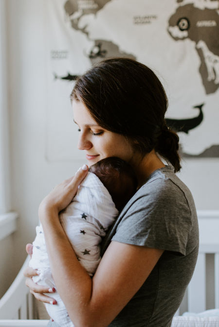 Eine Mutter umarmt ihr in ein Handtuch gewickeltes Baby.