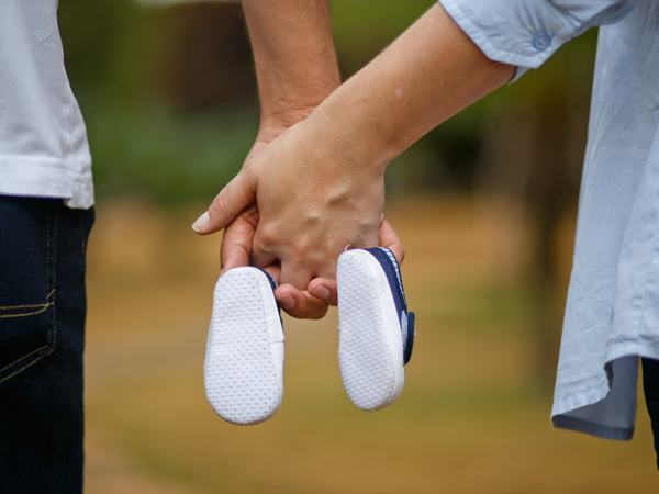 Aufnahme zwei sich haltender Hände mit Babyschuhen.