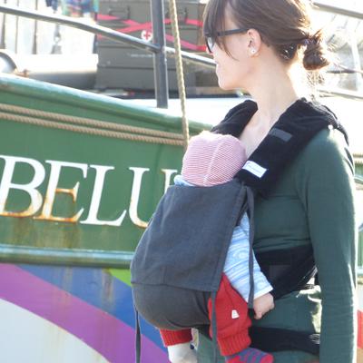 Ich trage meine Tochter in der Tragehilfe Mein Zwergennest von Mein Tragling in Flensburg. Wir stehen vor einem Schiff namens Beluga.