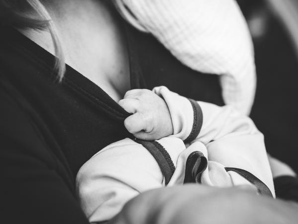 Teilaufnahme einer Frau, die ein Baby auf dem Arm hält.