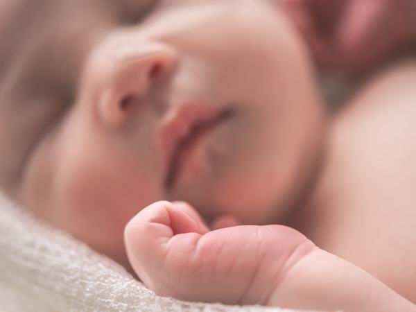 Detailaufnahme eines schlafenden Babys, wobei die entspannte Hand im Fokus steht.