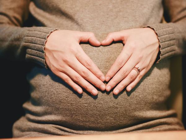 Aufnahme eines Babybauchs, über dem Hände ein Herz formen.