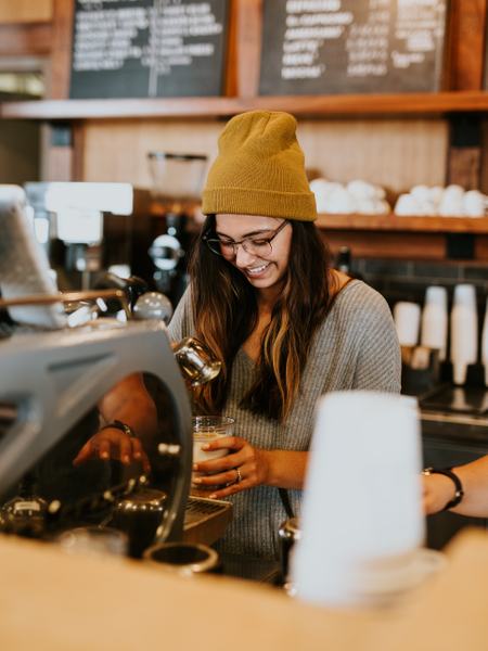 Aufnahme einer Frau, die einen Milchkaffee zubereitet.