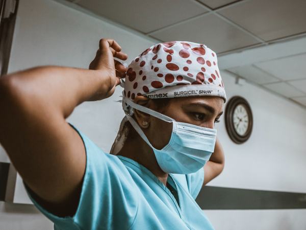 Aufnahme einer Frau in Klinikkleidung und Mundschutz.