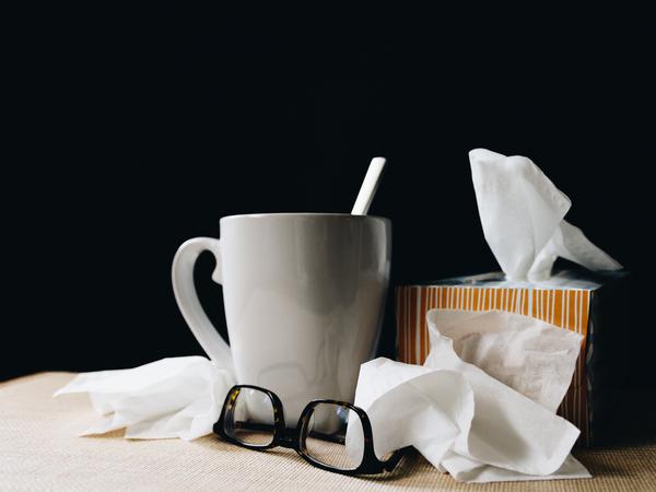 Foto einer Tasse, einer Brille und einer Packung Taschentücher.