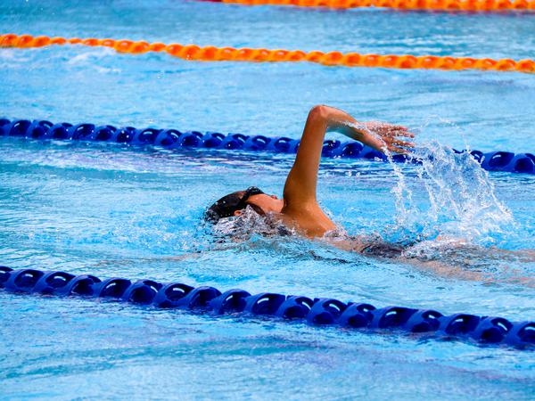 Foto einer Frau, die in einem Schwimmbecken am Kraulen ist.