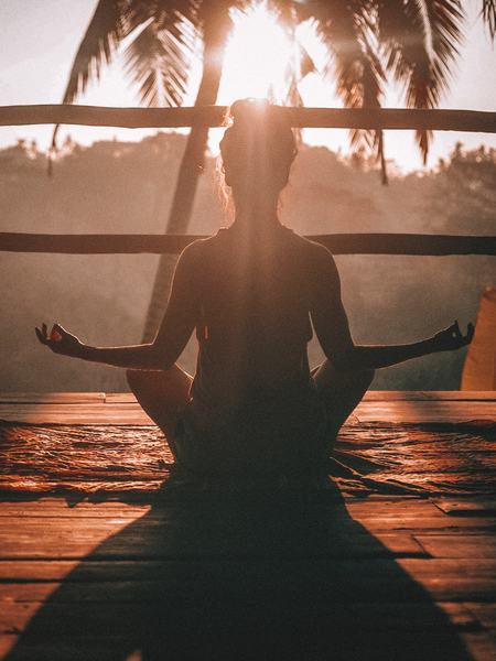 Aufnahme einer Frau, welche in einer sitzenden Yogaposition zu sehen ist.