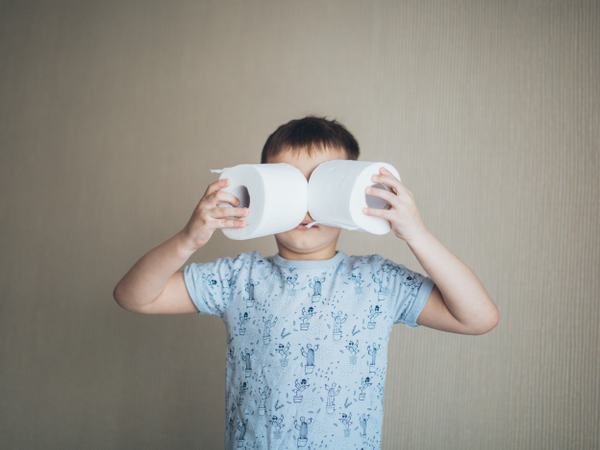 Ein Kind steht und hält sich jeweils eine Klopapierrolle vor die Augen