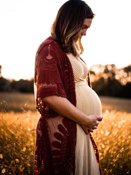 Eine schwangere Frau steht in einem Feld.