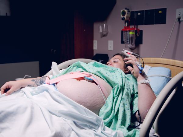 Eine schwangere Frau liegend im Bett mit CTG-Gurt.