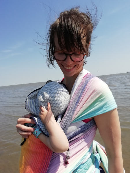 Ich trage meine Tochter vor dem Bauch am Strand.