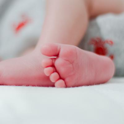 Die Füße eines Babys in einer NAhaufnahme. Im Hintergrund sieht man nur verschwommen einen Body.
