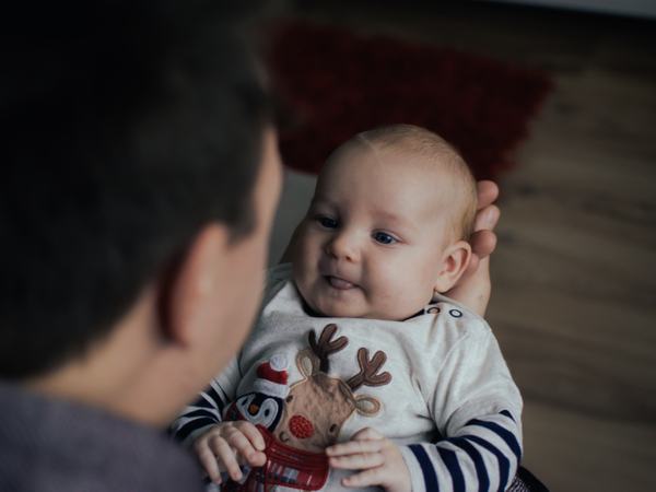 Aufnahme eines Baby, welches versucht die Zunge herauszustrecken, während es auf dem Arm gehalten wird.