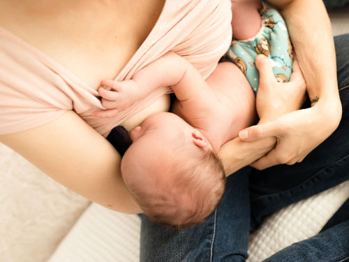 Ein Säugling wird von seiner Mutter gestillt.